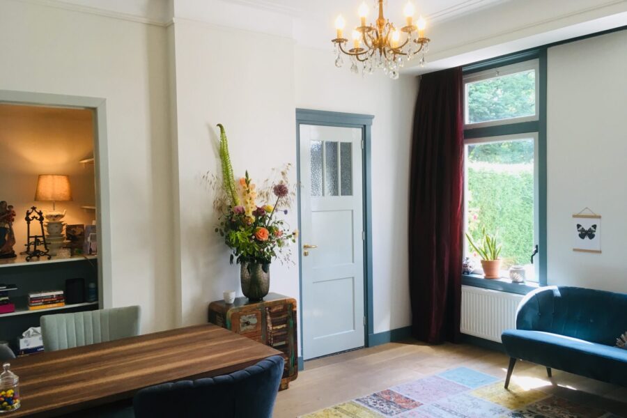 Lichte woonkamer in het afscheidshuis met eettafel, bloemen en een kroonluchter