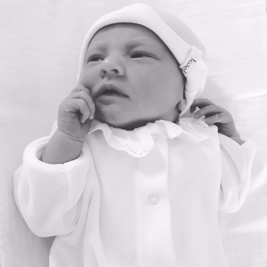 Zwart-witfoto van een baby in een wit pakje