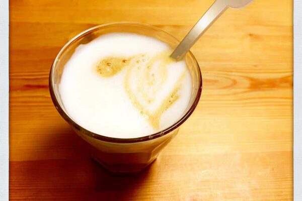 Kop koffie met melkschuim op een houten tafel
