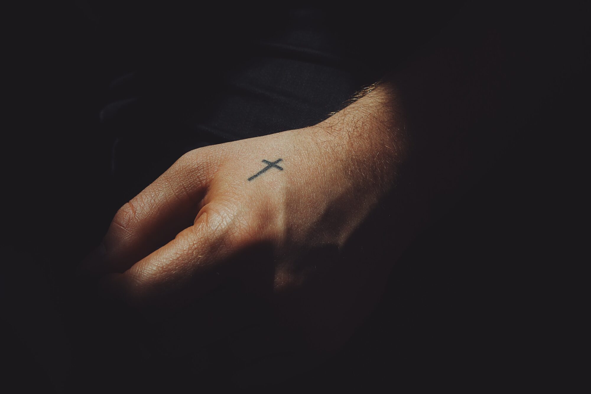 Een getatoeëerd kruisje op een hand