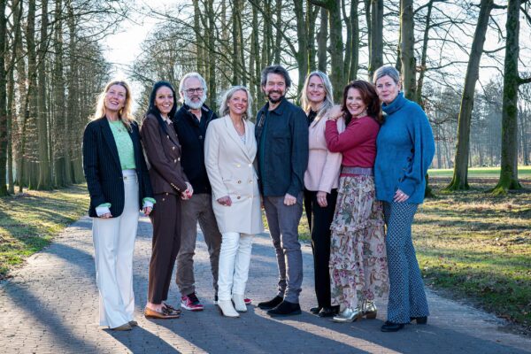 Het team van Marinka de Haan staat samen op een laan met bomen