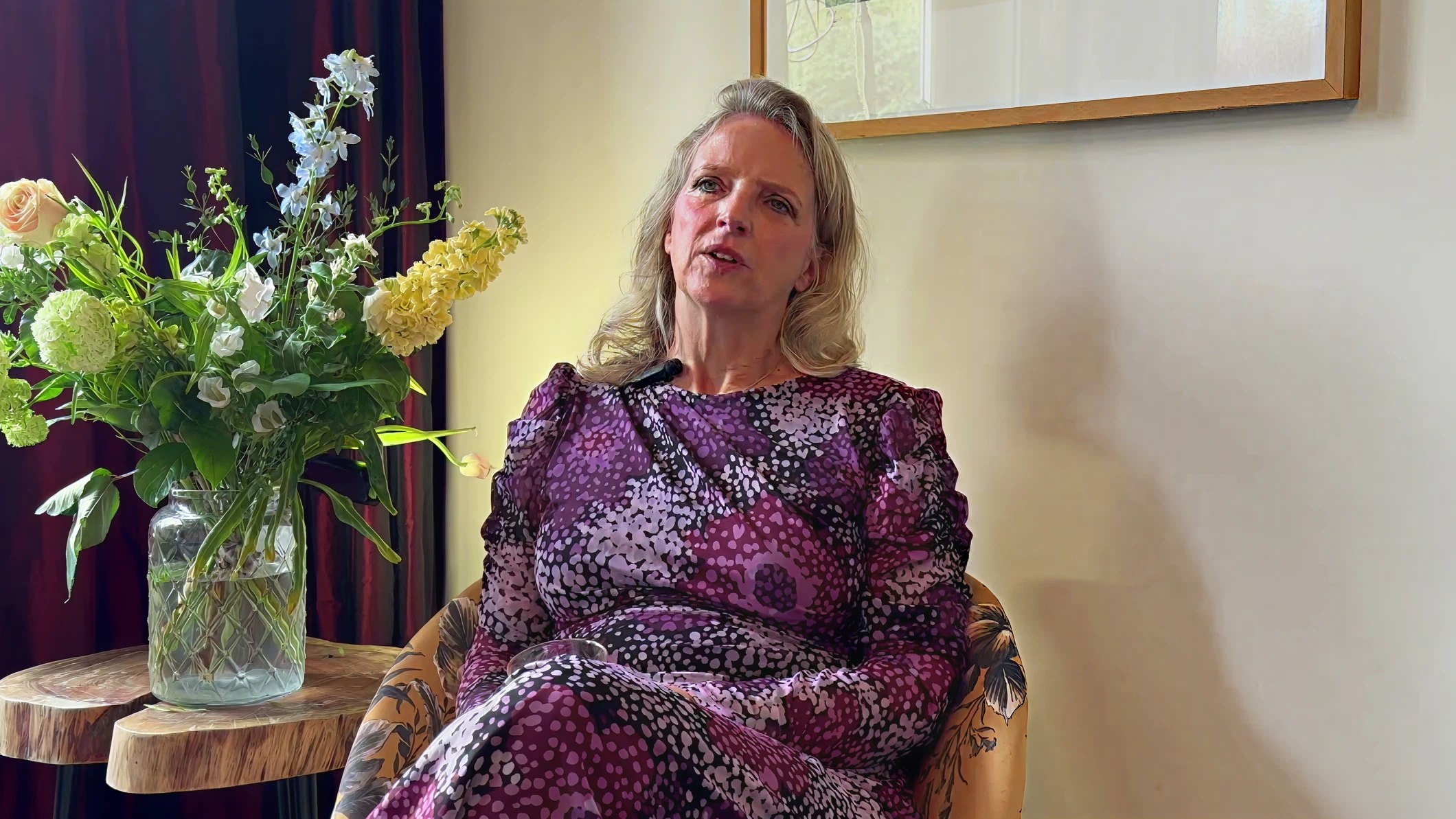 Marinka de Haan zit in een stoel naast een vaas met bloemen tijdens een interview